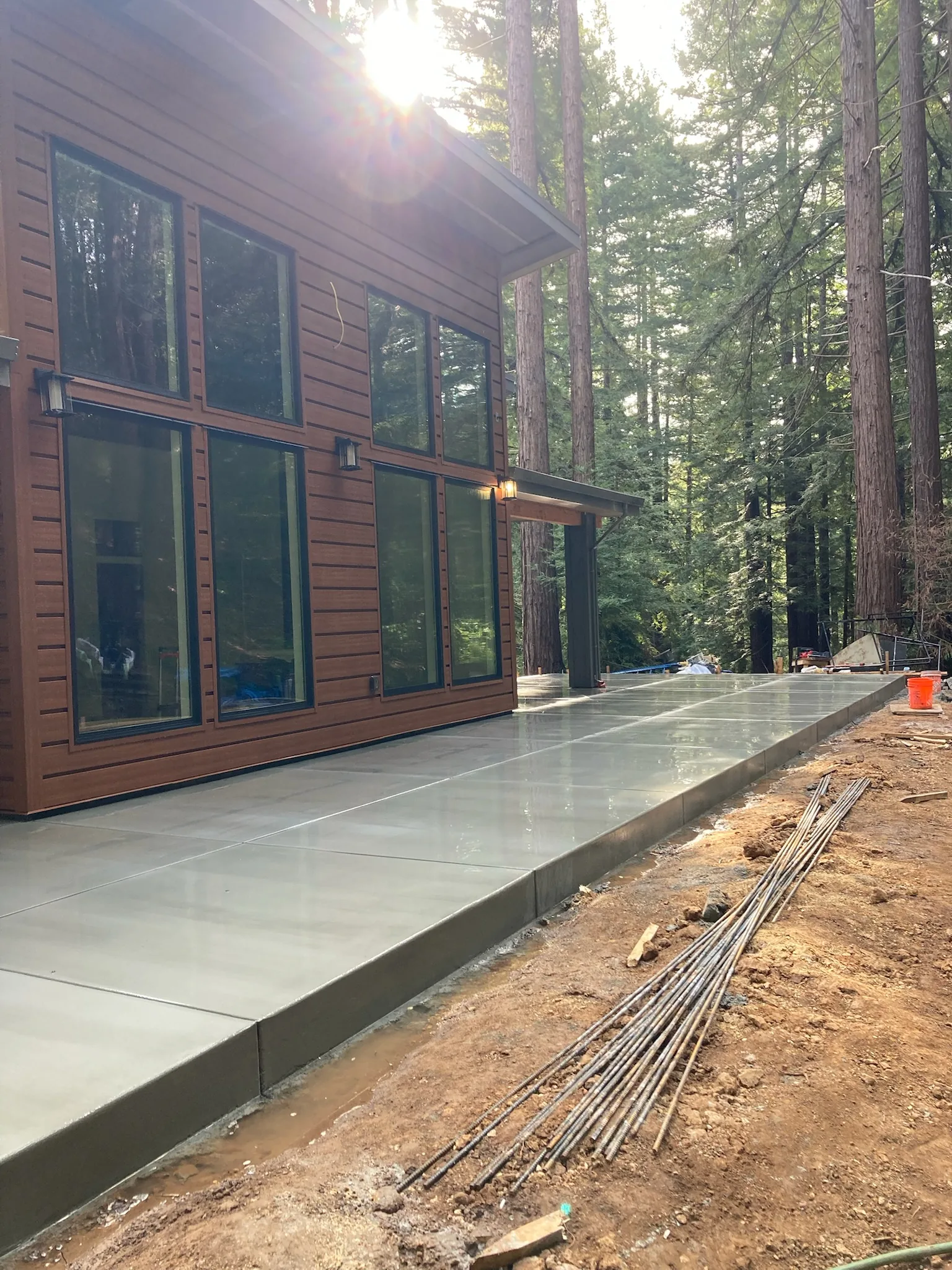 Freshly finished concrete patio around a modern home in a wooded setting